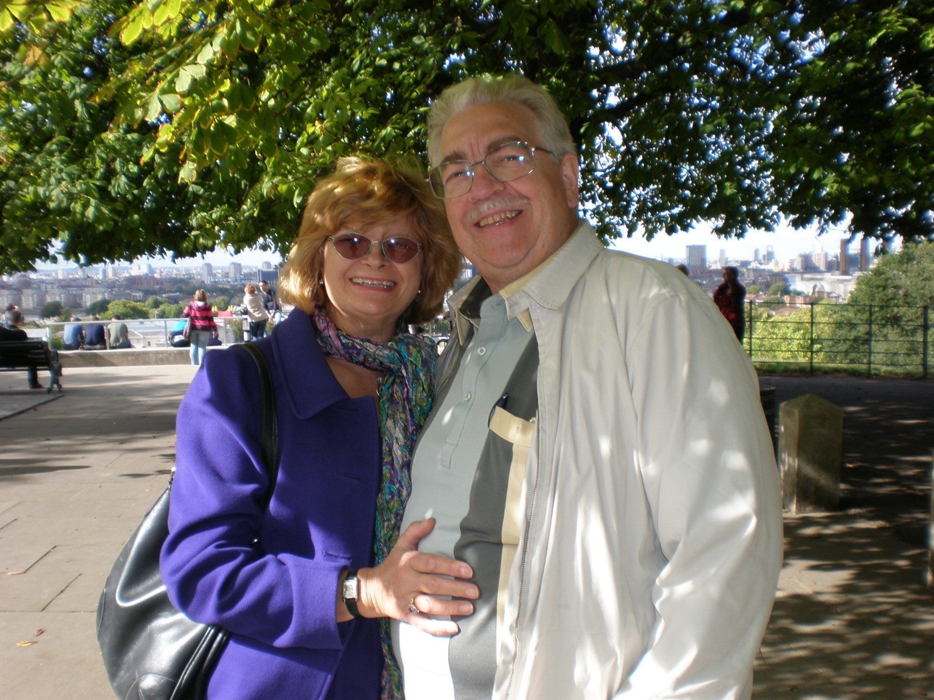 A man and woman are posing for a picture under a tree