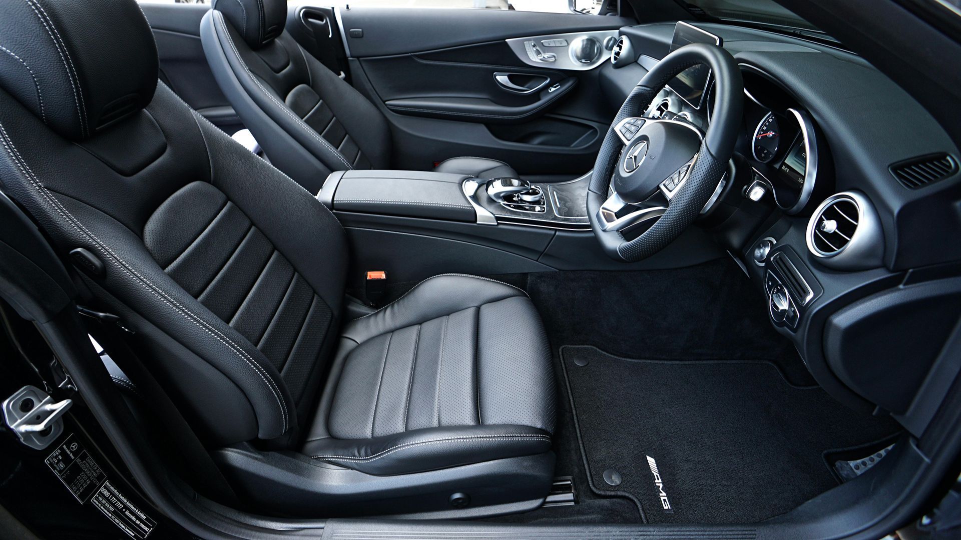 Black interior of a Mercedes convertible, showing leather seats, dashboard, and steering wheel.
