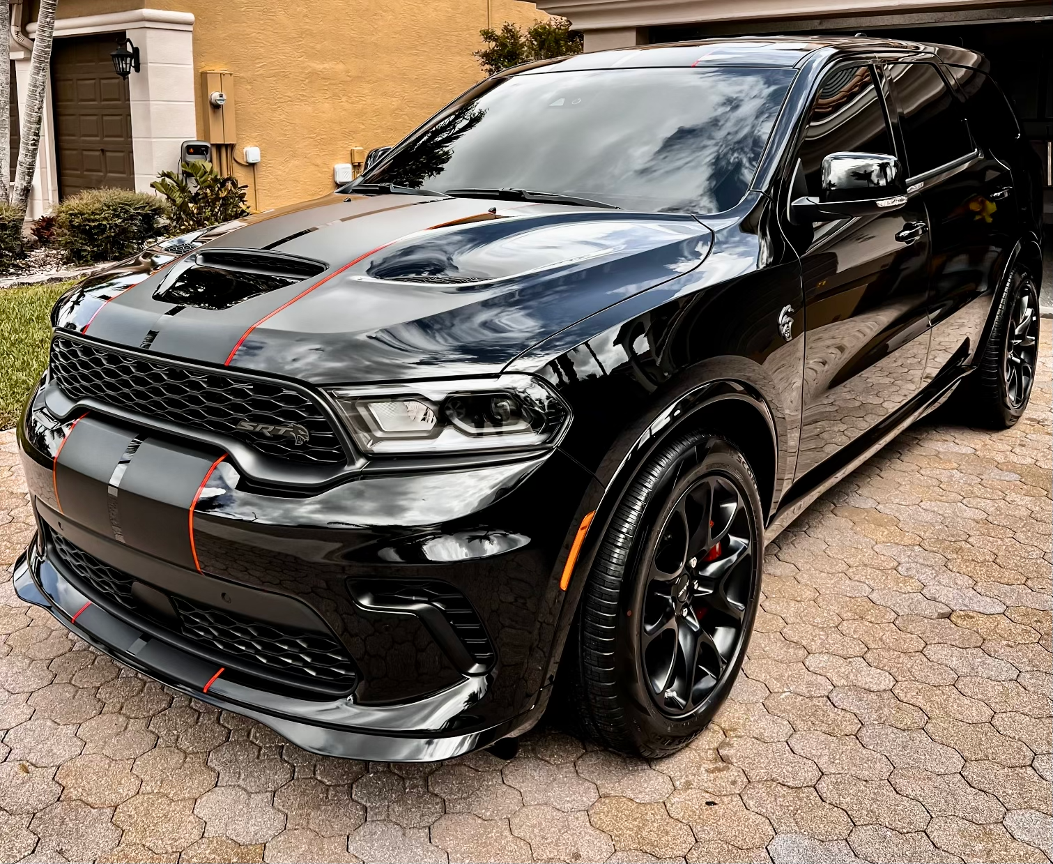 Black Dodge Durango SUV with red stripes, parked on a brick driveway.