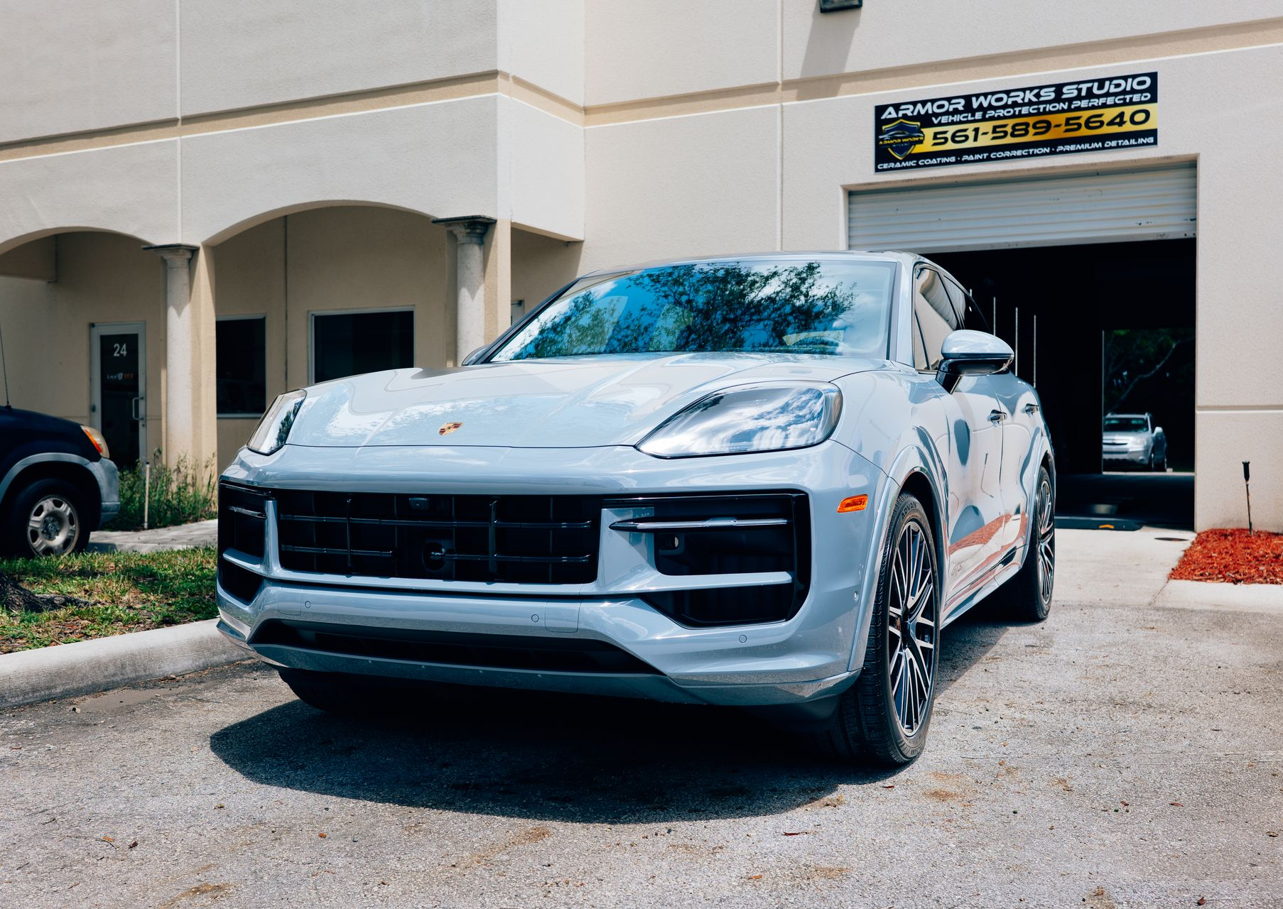 Gray Porsche SUV parked in front of a building with a garage door.