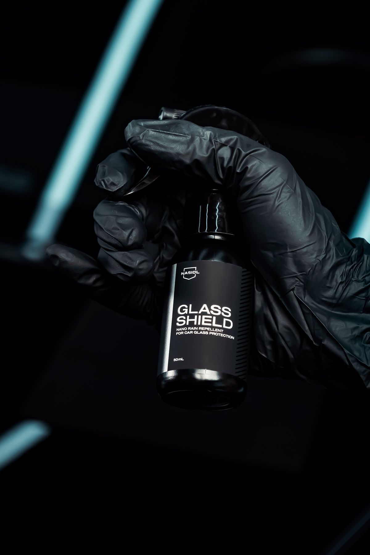 Gloved hand holding a black bottle labeled