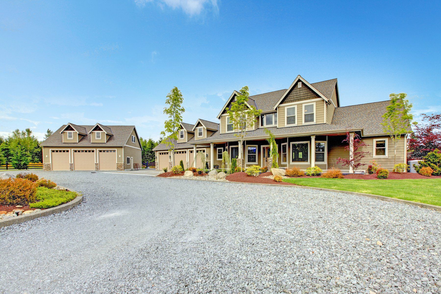 An outdoor view of a gravel driveway leading up to a rustic home, with a mix of small and medium-sized stones neatly spread across the ground.