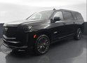 A black cadillac escalade is parked in a showroom.