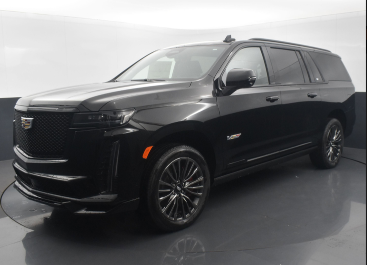 A black cadillac escalade is parked in a showroom.