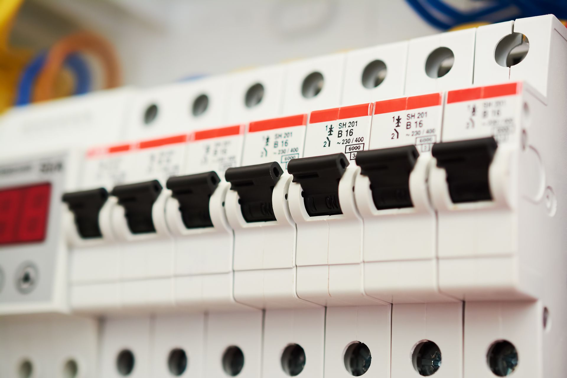 Close-up of a white electrical panel with multiple black circuit breakers in the