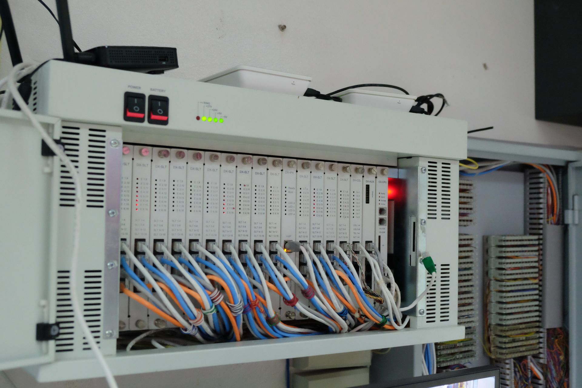 Network server with multiple connected cables, rack-mounted, white and gray with red and green indicator lights.