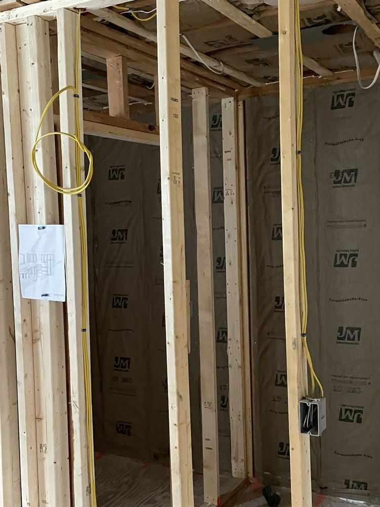 Interior wall framing with electrical wiring, insulation, and an electrical box.