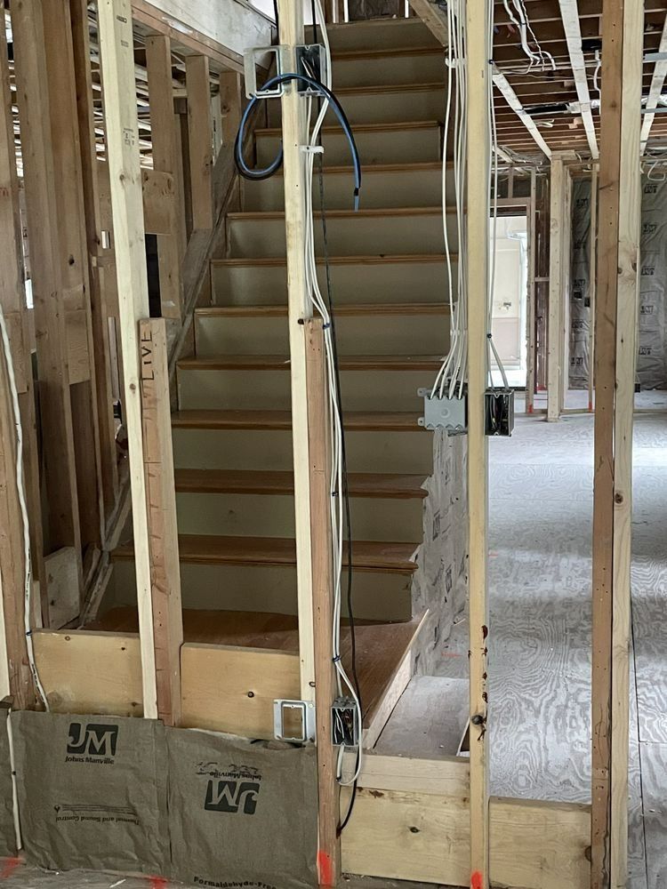 Wooden staircase under construction with exposed framing and wiring.