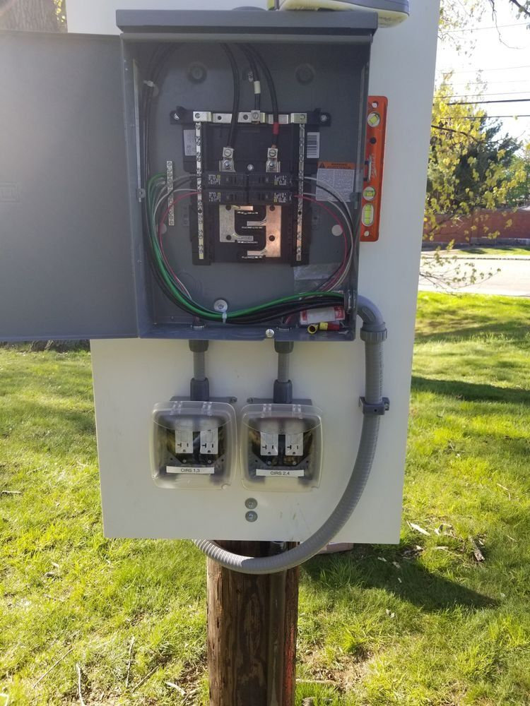 Outdoor electrical box with two outlets and a level on a wooden post.