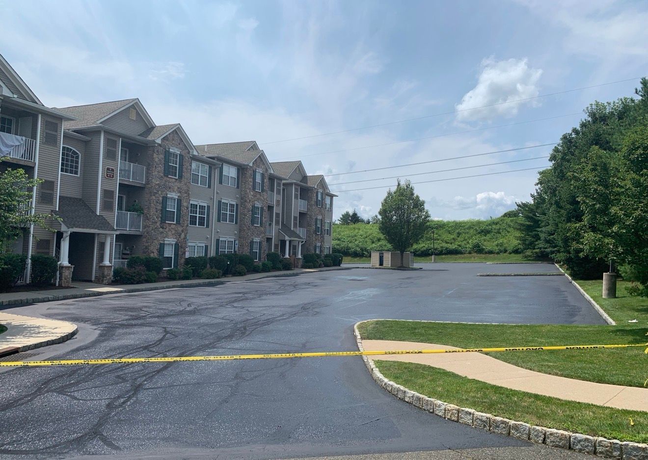 An apartment building with a paved parking lot cordoned off by yellow caution tape.