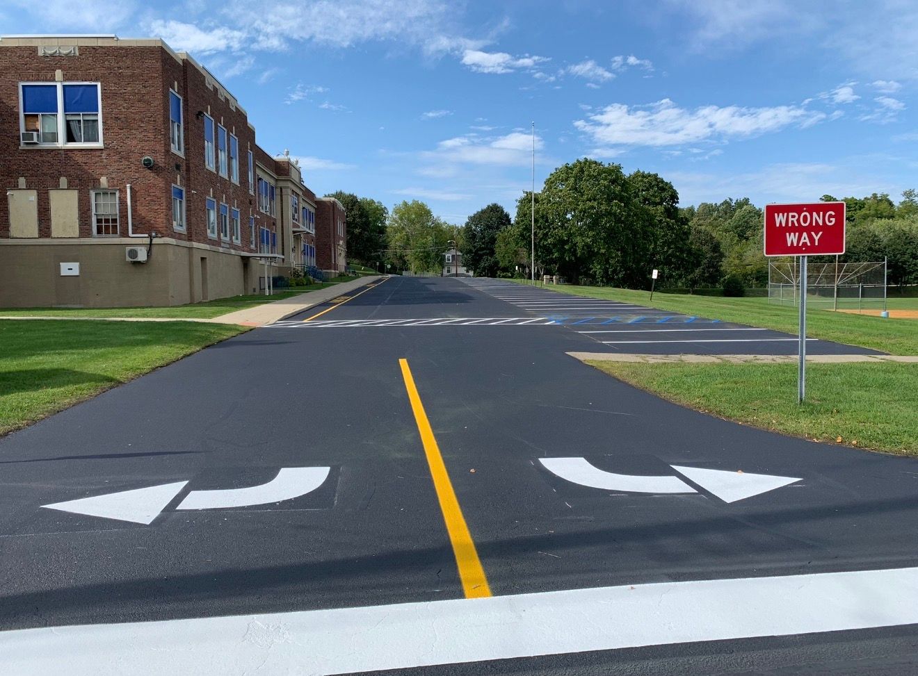 A newly paved road with directional arrows, a yellow center line, and a red 