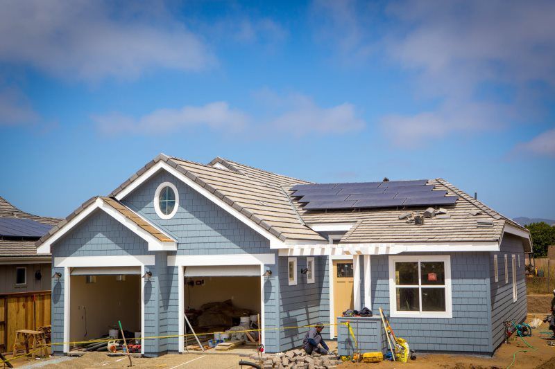 A house is being built with solar panels on the roof.