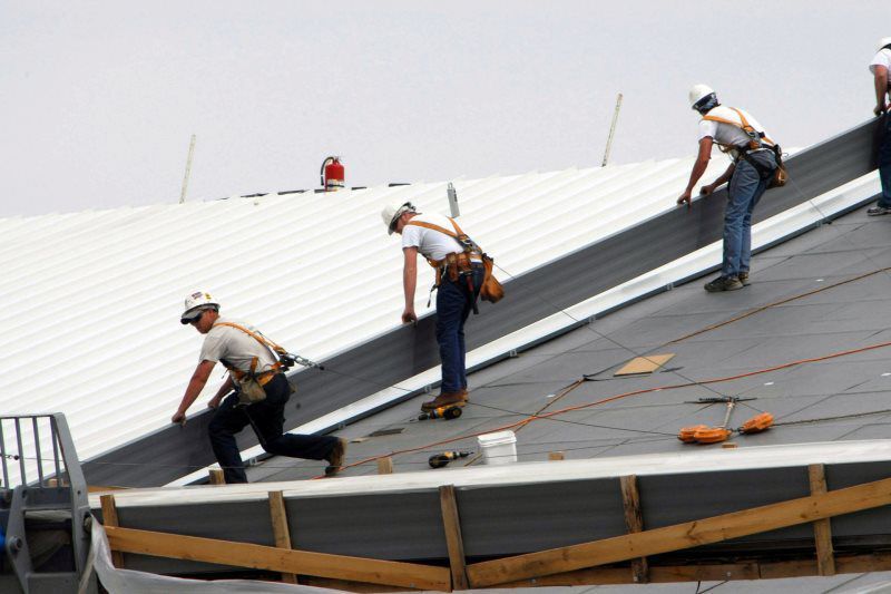 A group of construction workers are working on the roof of a building.