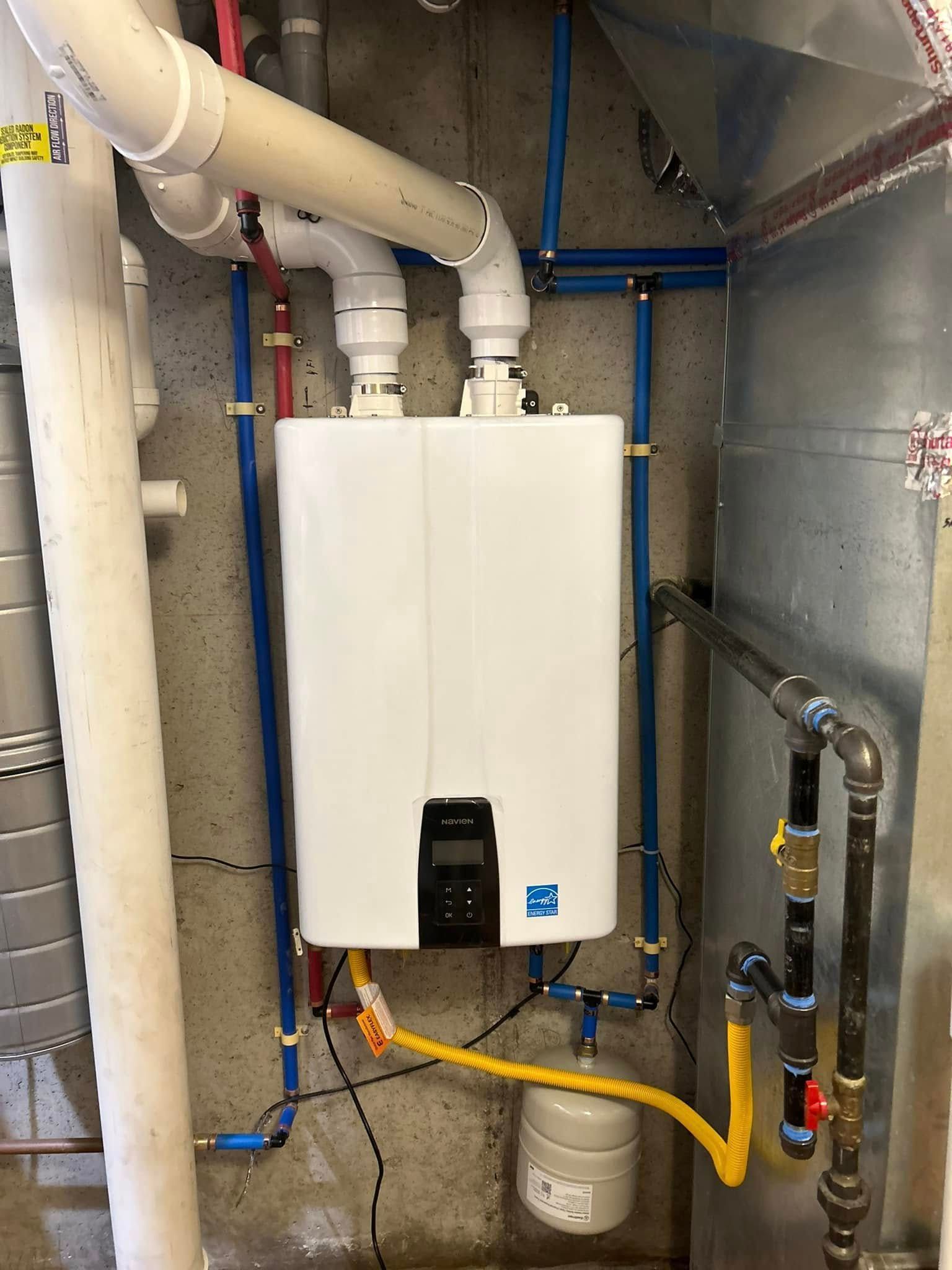 Tankless water heater installed in a basement, with associated pipes and connections.
