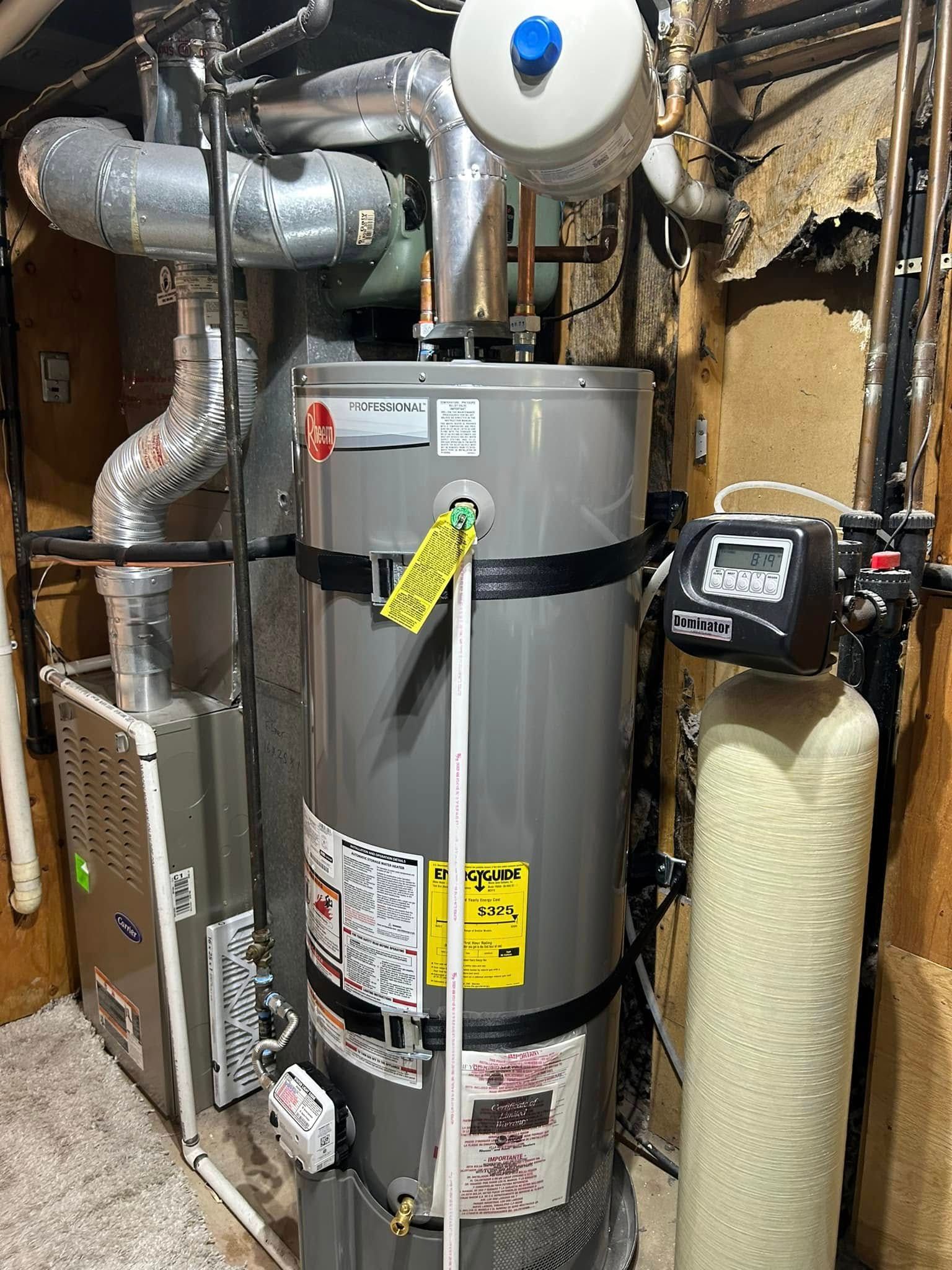 Water heater and furnace in a utility room. Gray tank with pipes, white and yellow labels.