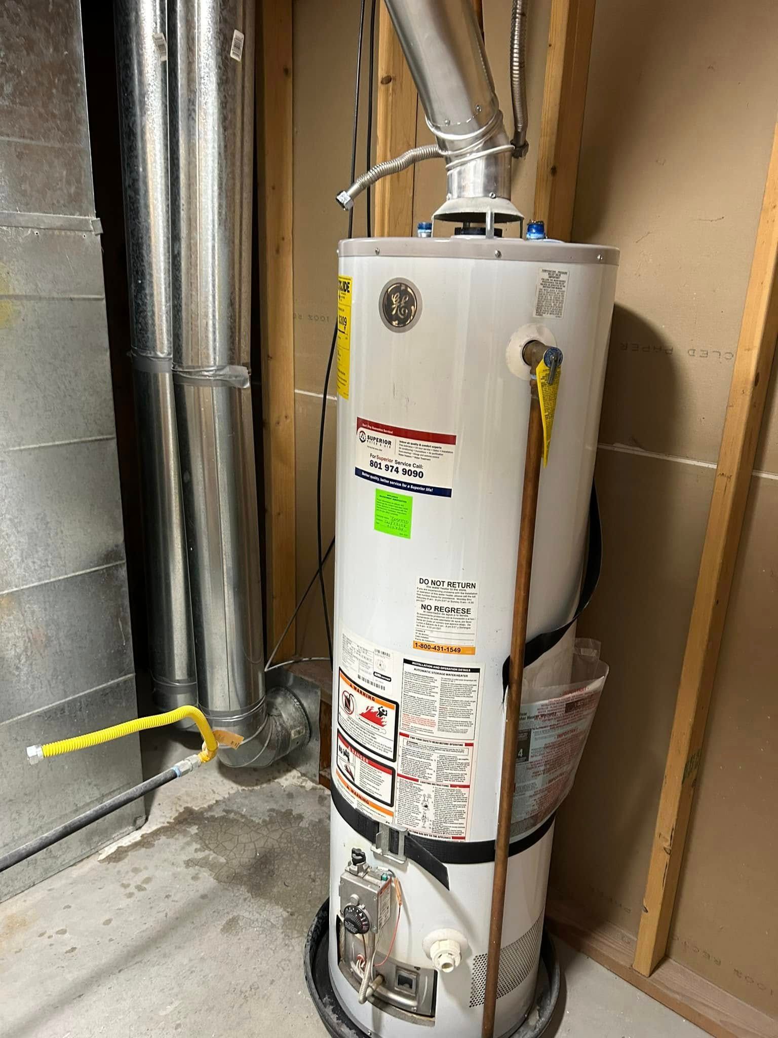 A gas water heater in a utility room, with vents and pipes visible.