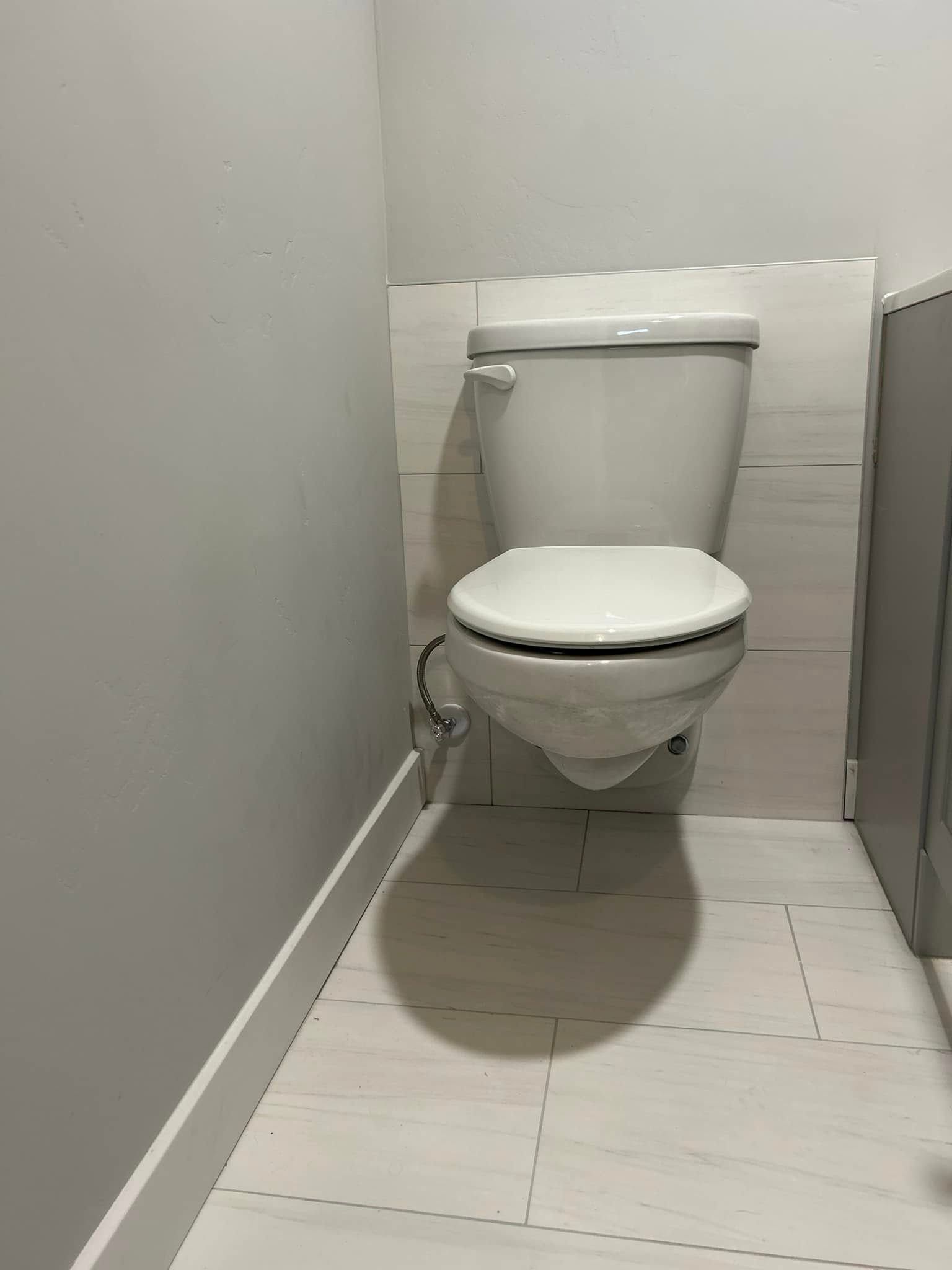 White toilet in a small bathroom with tile floor and light gray walls.