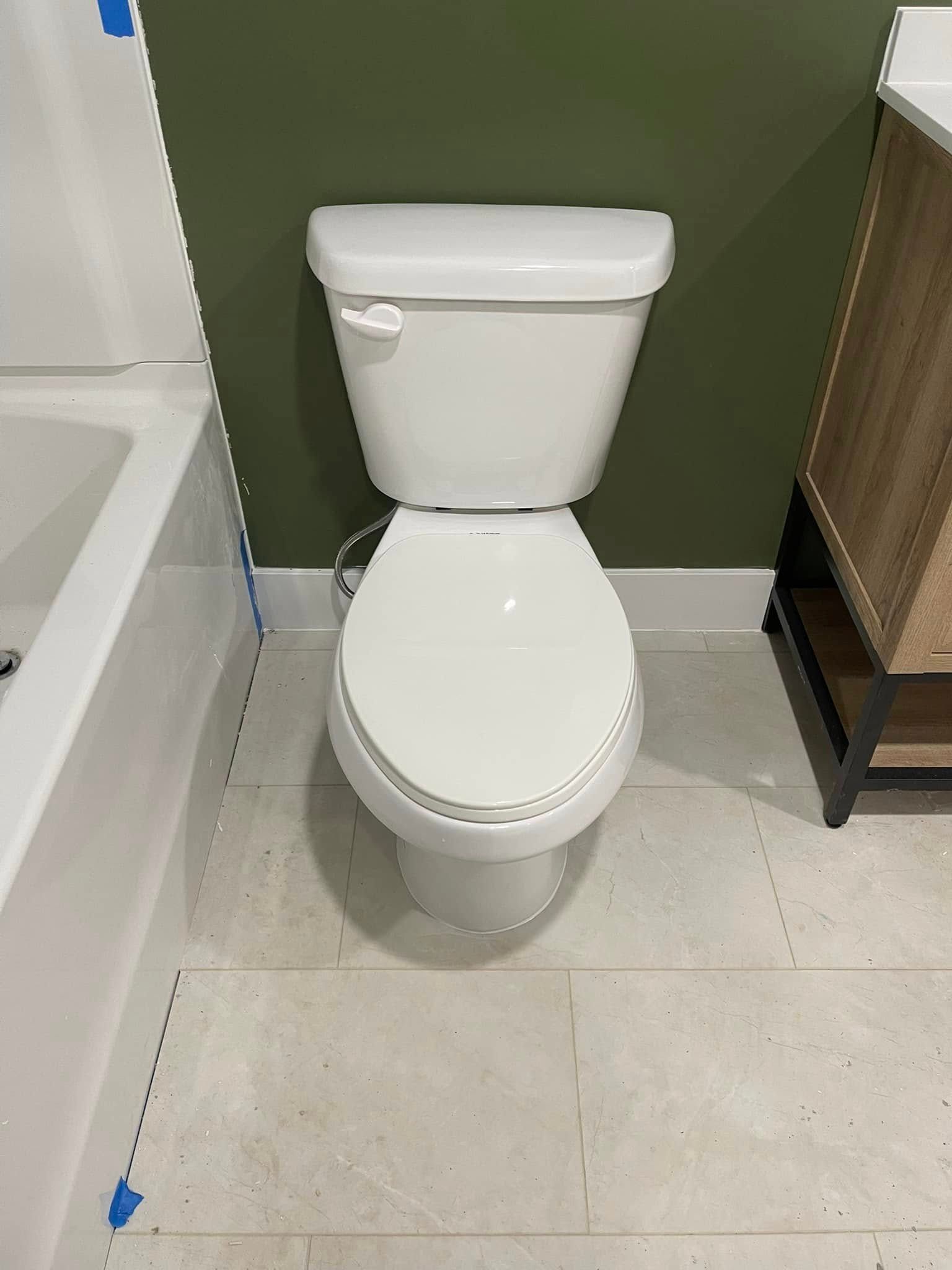 White toilet in a bathroom with light tile floors and dark green wall.