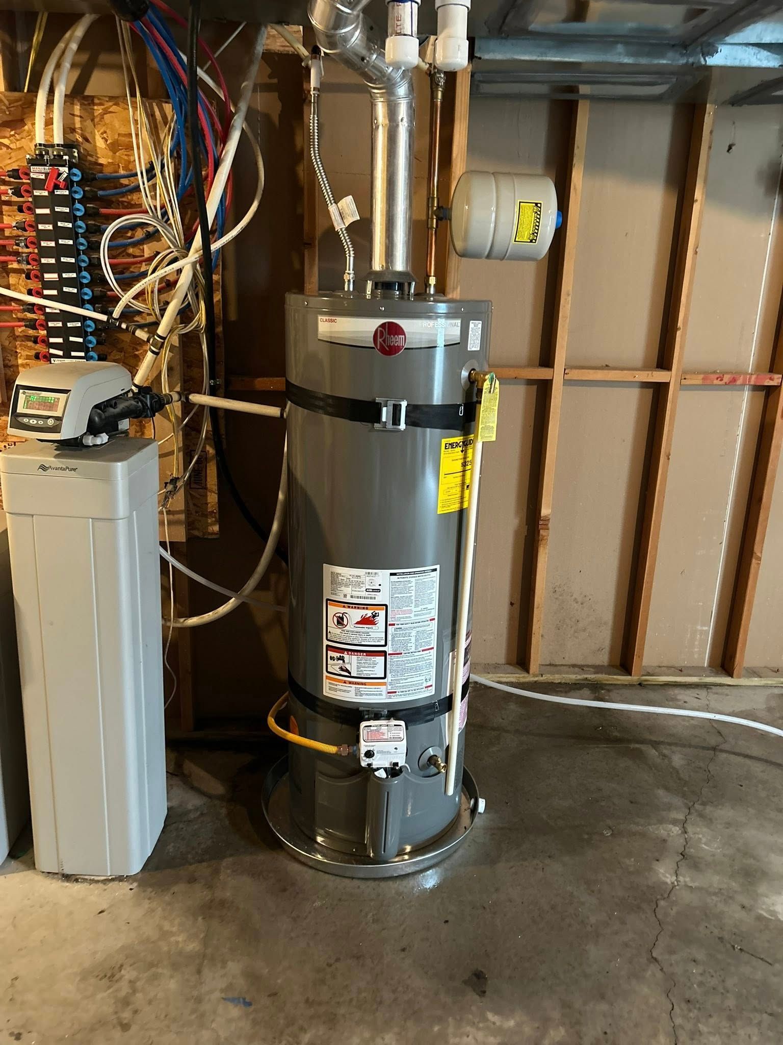 Water heater, water softener, and electrical panel in a basement.