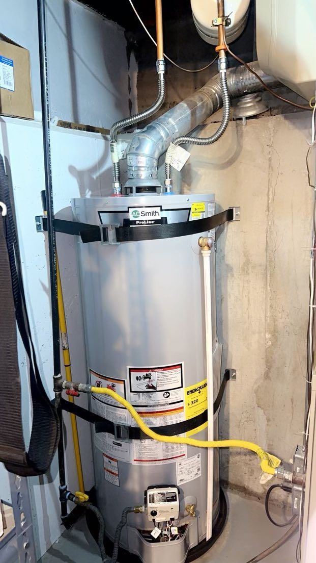 Water heater in a basement setting with vent pipe, gas line, and support straps.