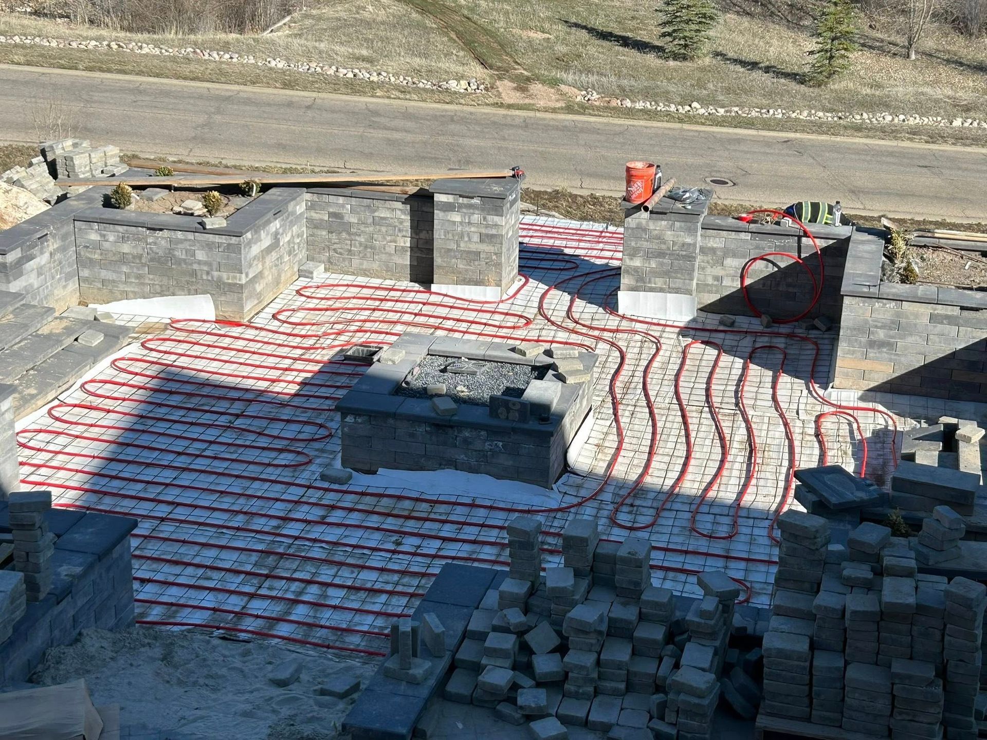 Construction site with red tubing for radiant floor heating laid within a foundation of gray block walls.