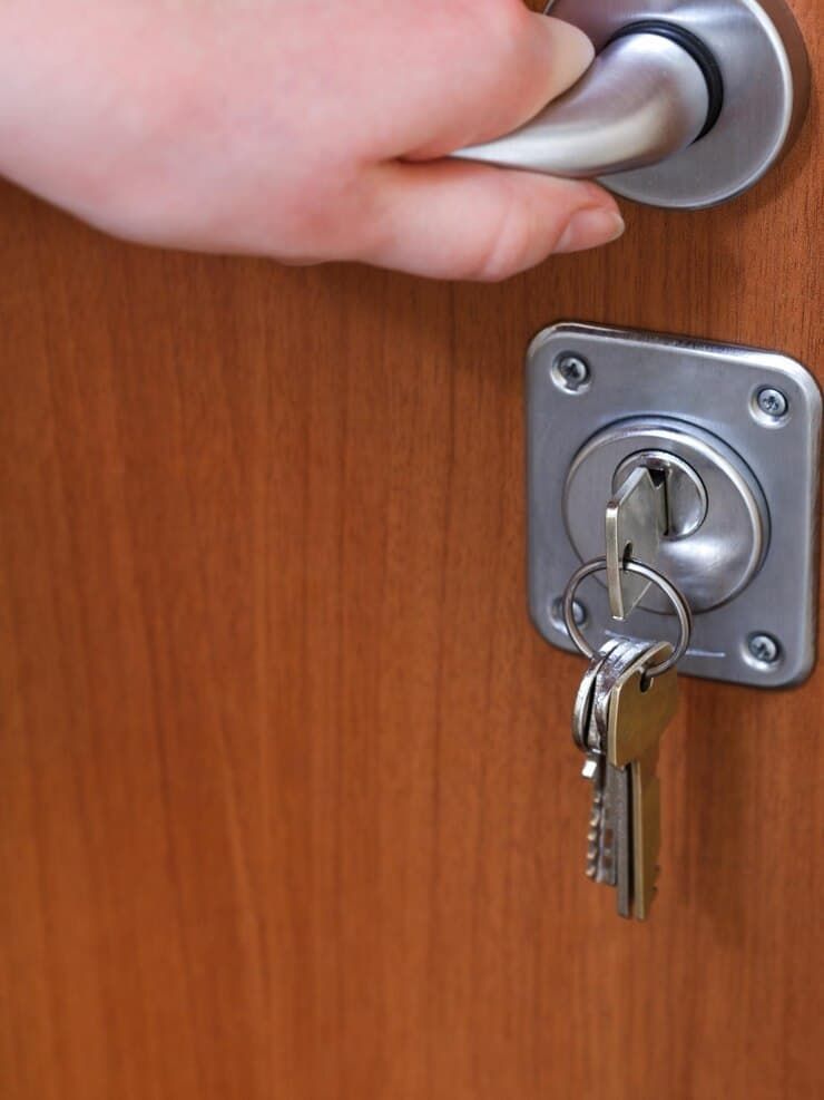A Person Is Opening a Door with A Key in The Lock — East Coast Locksmiths in Laurieton, NSW