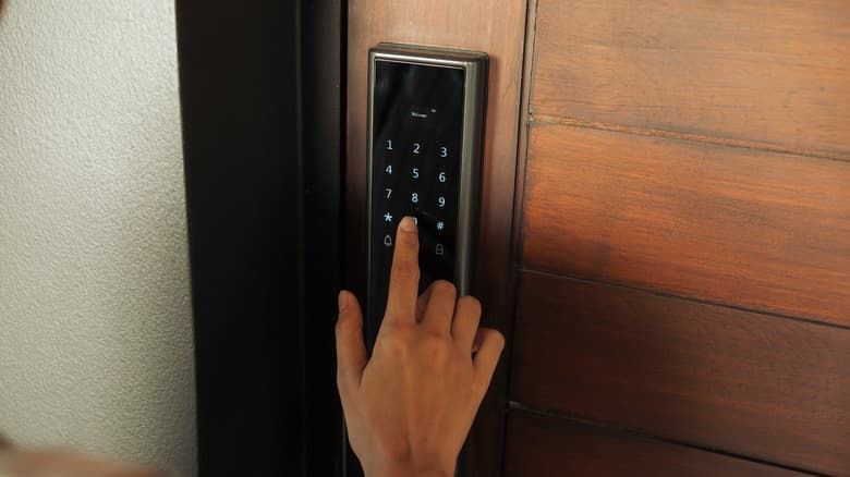 A Person Is Pressing a Button on A Door Lock — East Coast Locksmiths in Kew, NSW