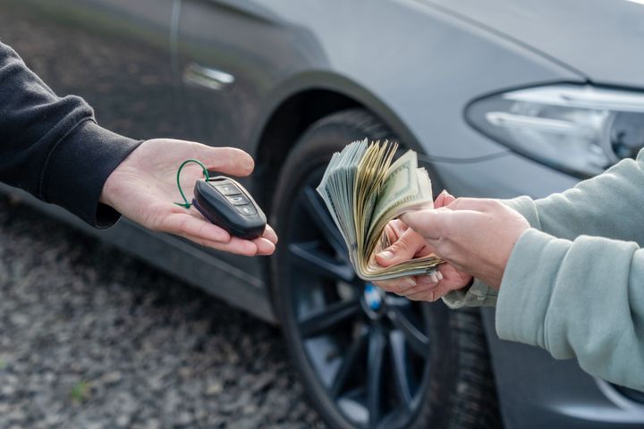 Deal of selling a car concept. Hand with the car keys, other hand gives money with a car behind. Deal of selling a car concept. Hand with the car keys, other hand gives money with a car behind.