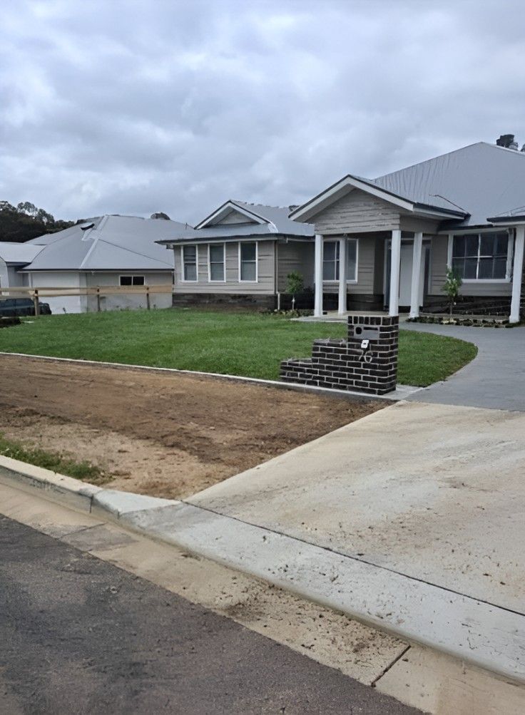 A Large White House With a Brick Mailbox in Front of It — Superior Turf in Illawarra, NSW