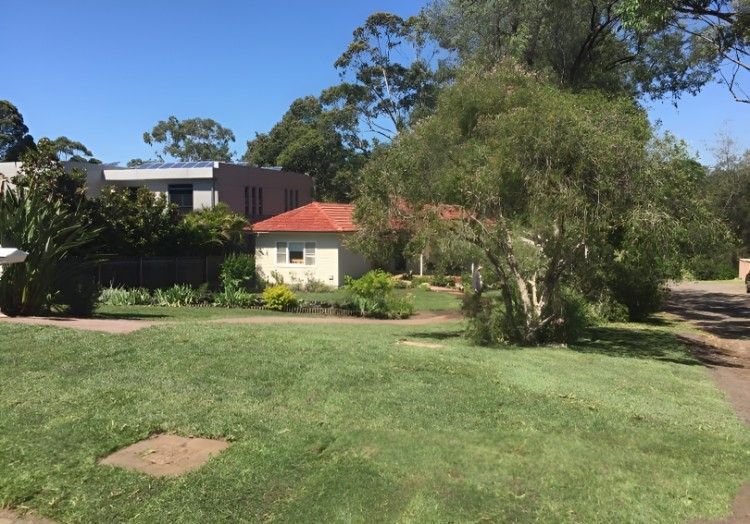 A House With a Red Tile Roof is Surrounded by Trees and Grass — Superior Turf in Illawarra, NSW