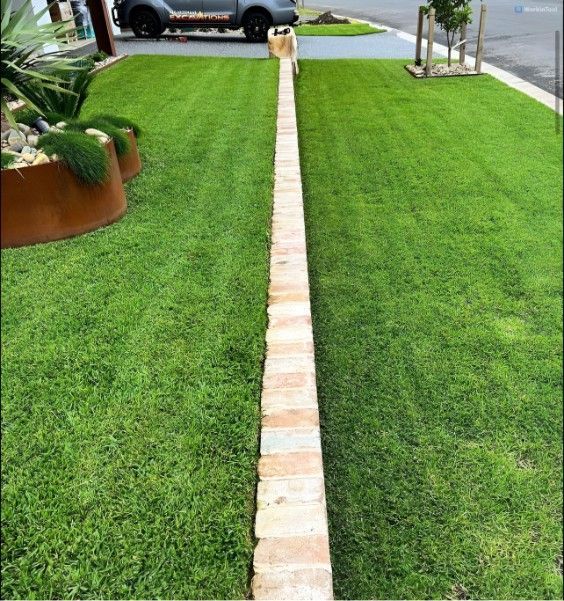 A Lush Green Lawn Next to a Brick Walkway — Superior Turf in Oak Flats, NSW