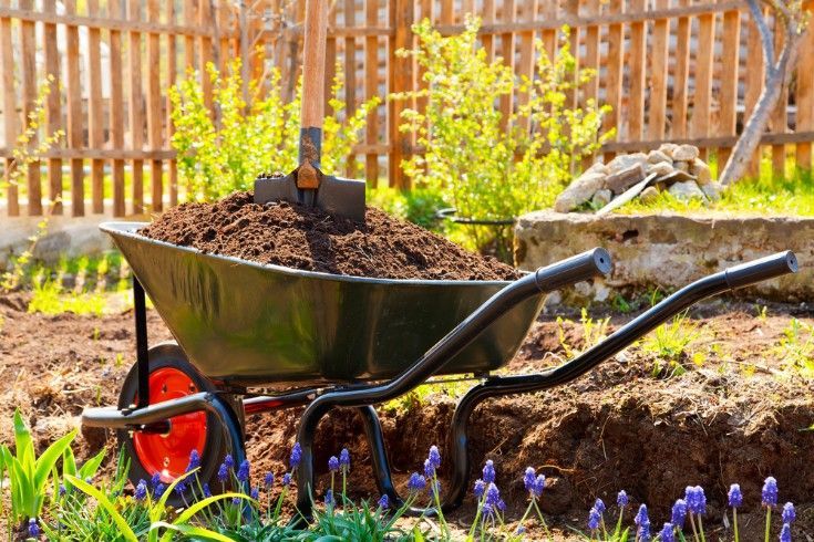 A Wheelbarrow Filled With Dirt and a Shovel in a Garden — Superior Turf in Shoalhaven, NSW