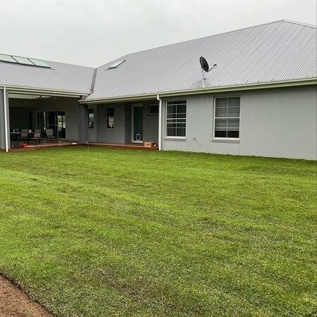 A Large Lawn in Front of a House With a Satellite Dish on the Roof — Superior Turf in Oak Flats, NSW