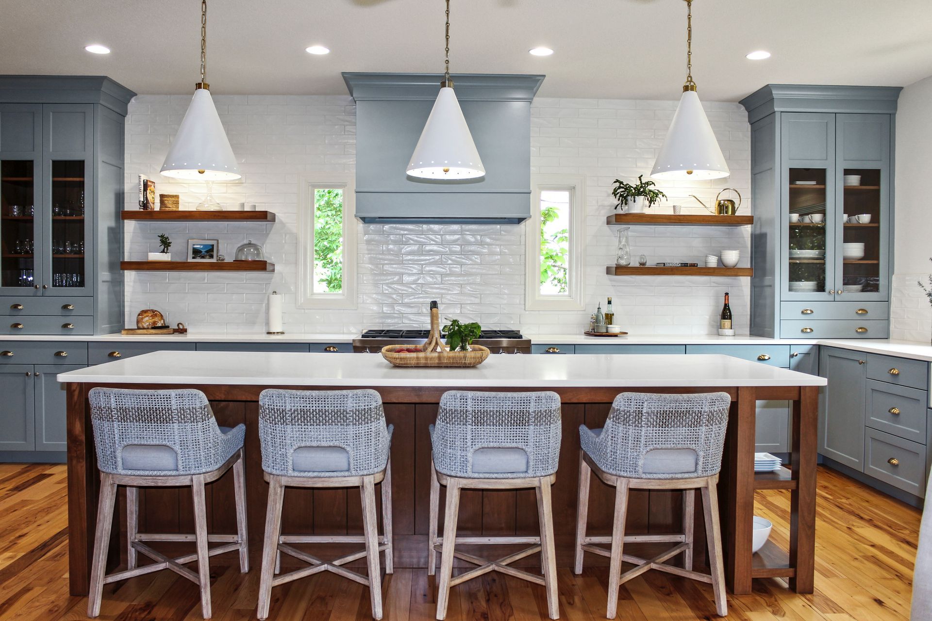A kitchen with blue cabinets , white counter tops , and wooden floors.