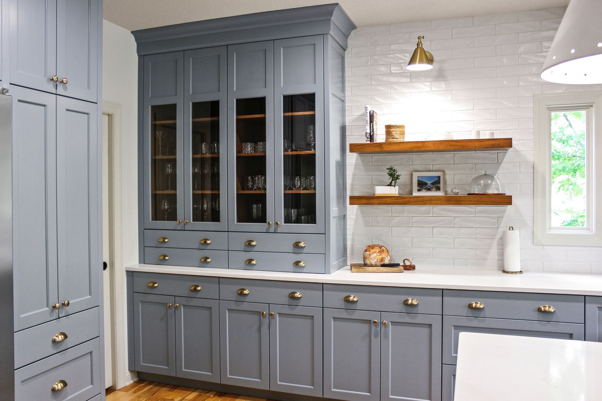 A kitchen with gray cabinets and white counter tops.