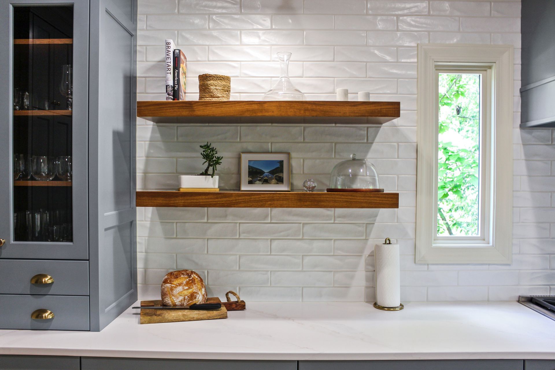 A kitchen with two wooden shelves and a window.