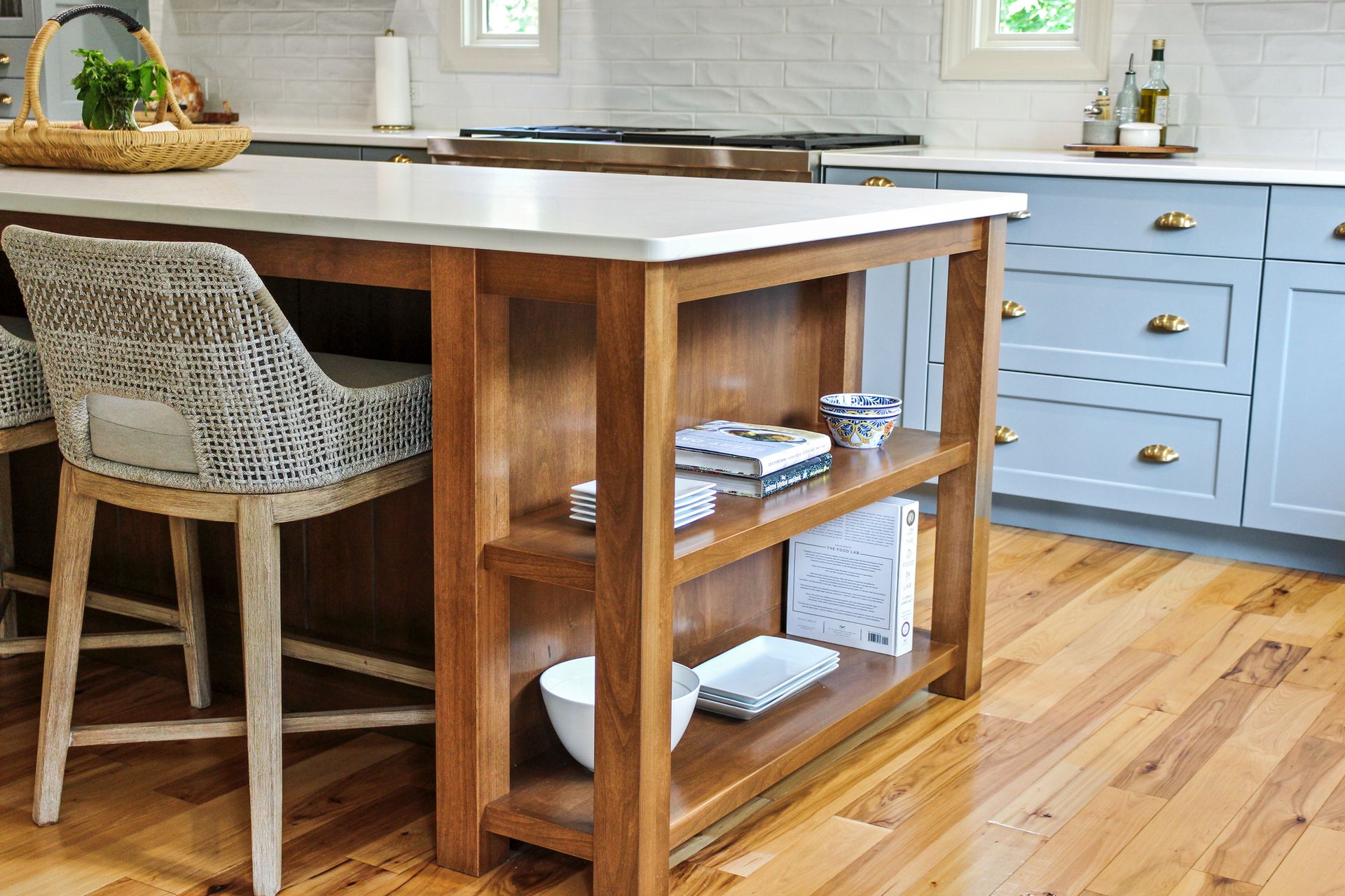A kitchen with a wooden island and wicker chairs.