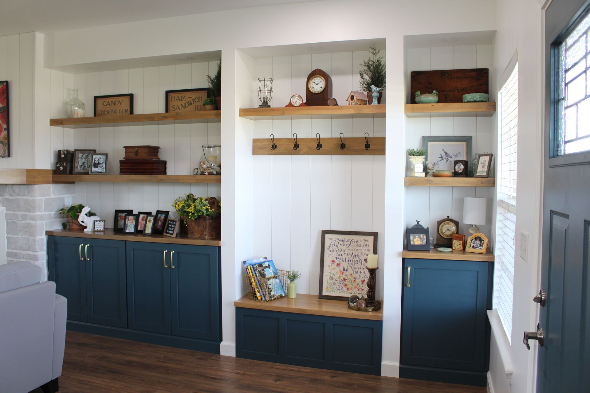A living room with a window seat filled with pillows and drawers.