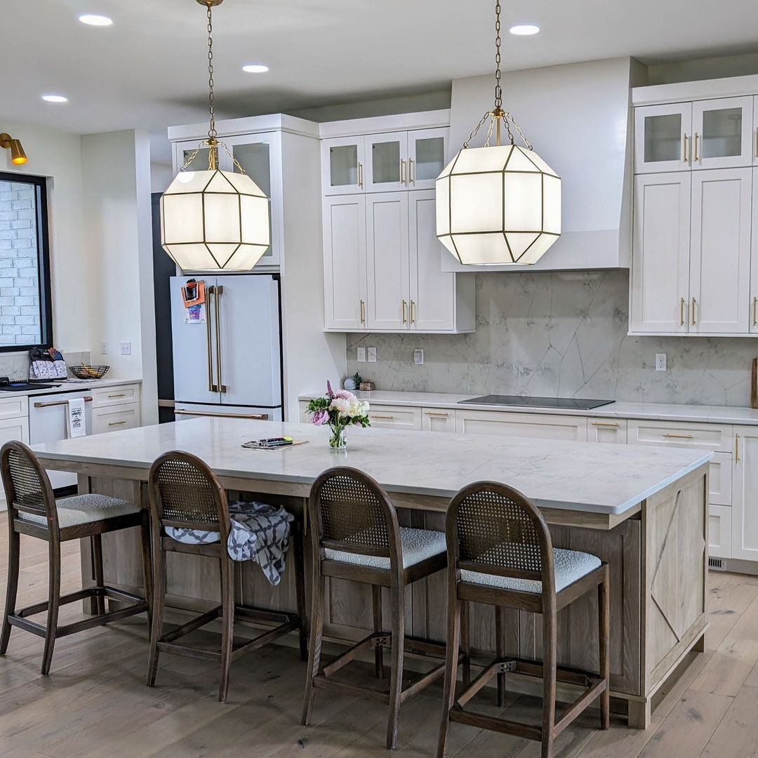 Dining nook with a leather tufted bench, wooden table, and two black chairs near a window.