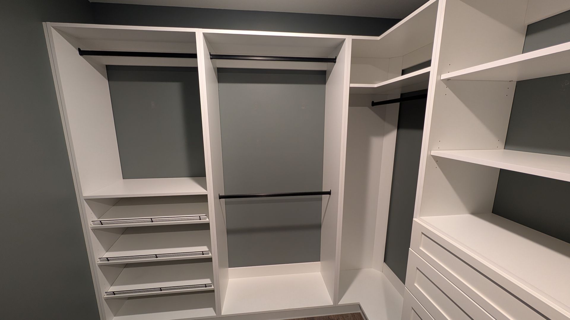 A walk in closet with a wooden dresser and shelves.