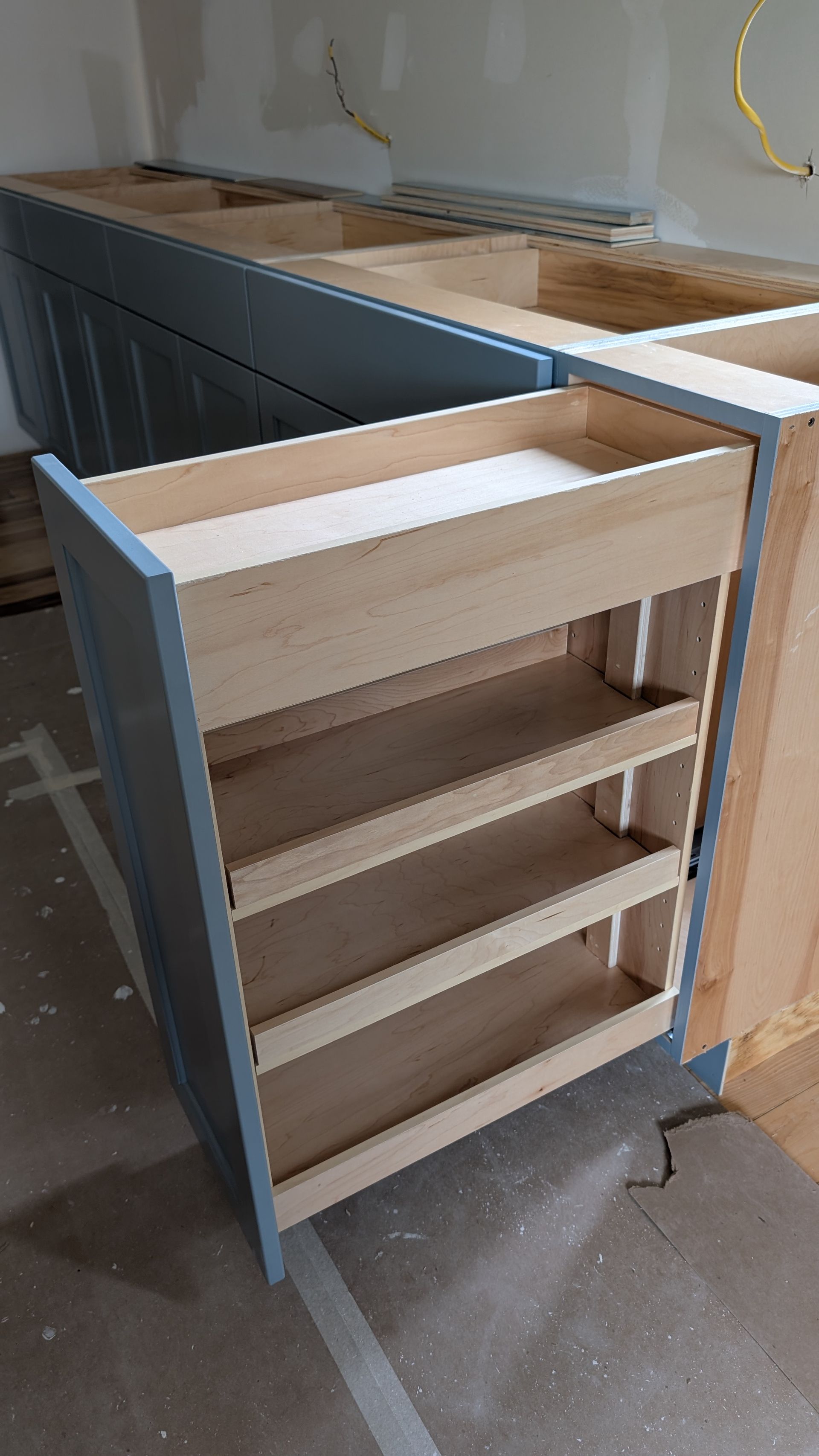 A kitchen cabinet is being built with wooden drawers.