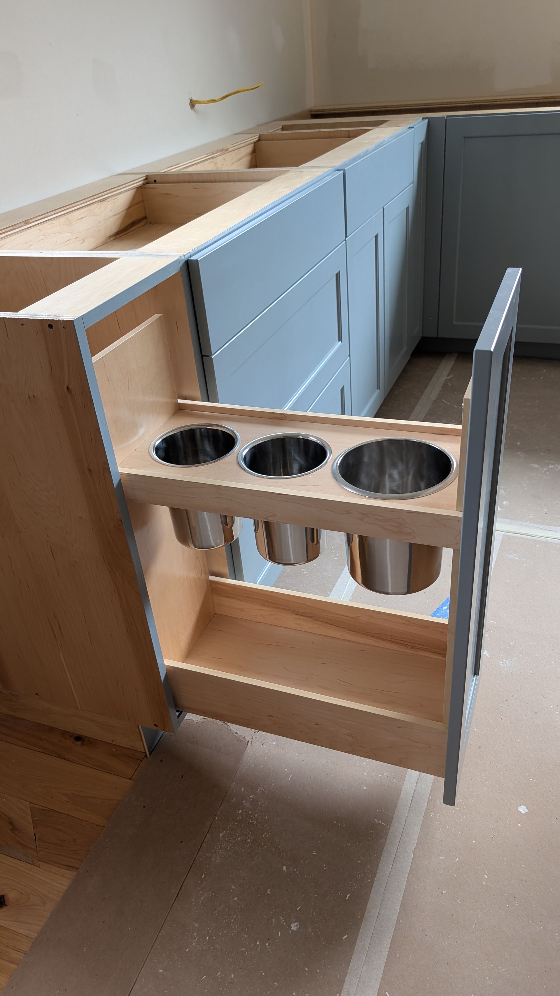 A kitchen cabinet with a pull out drawer filled with pots and pans.
