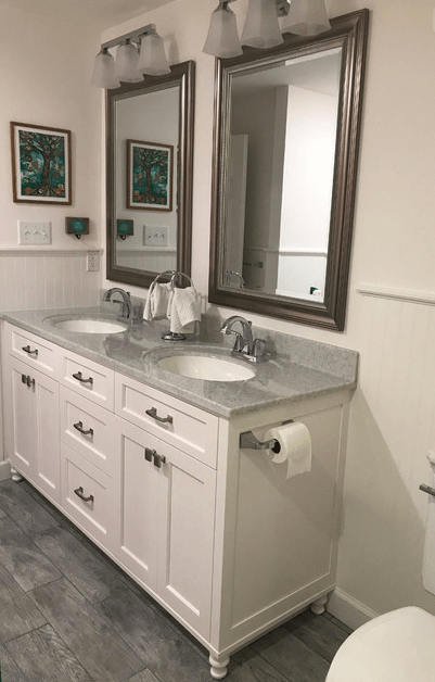 A bathroom with two sinks , two mirrors and a toilet.