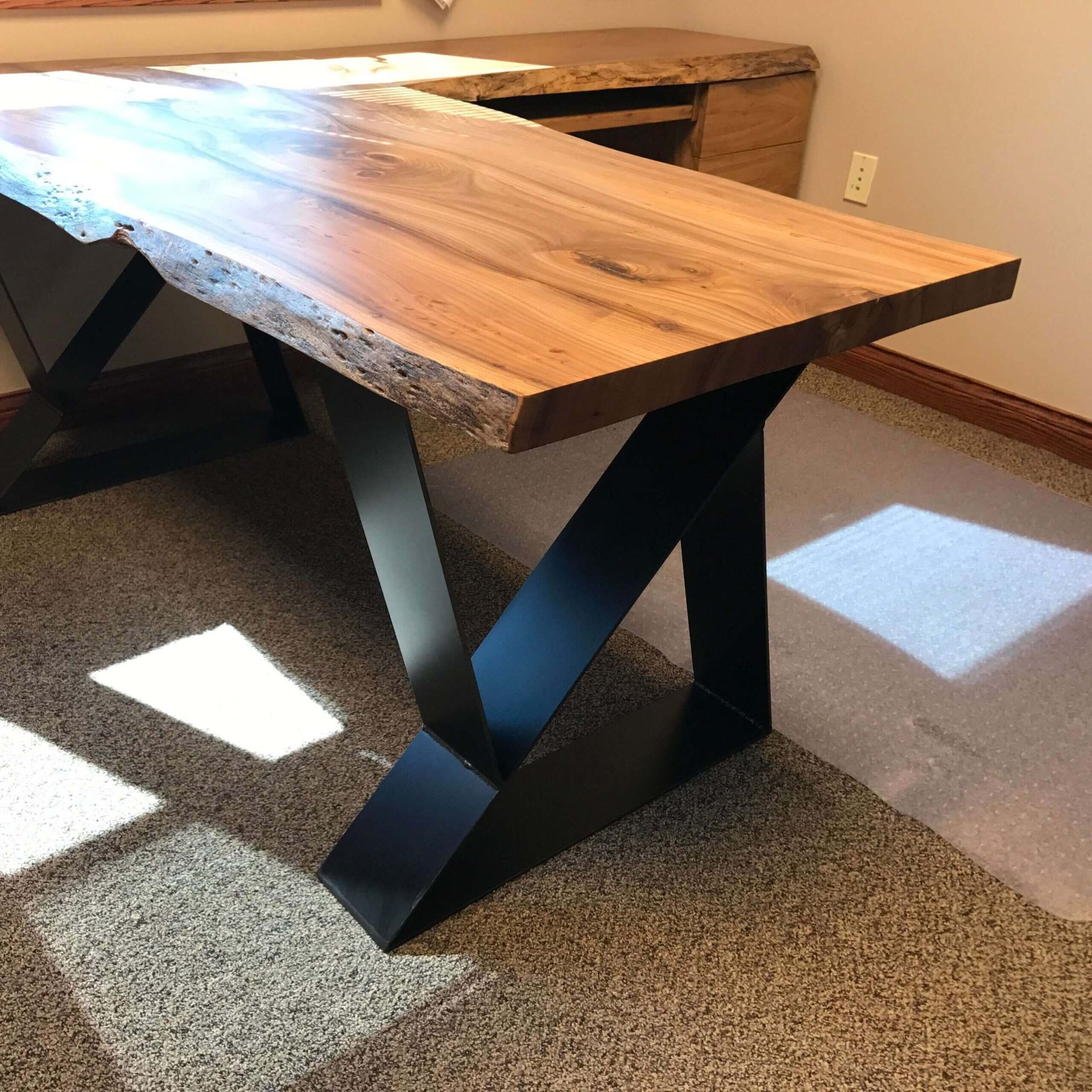 A wooden table with a black metal base in a room