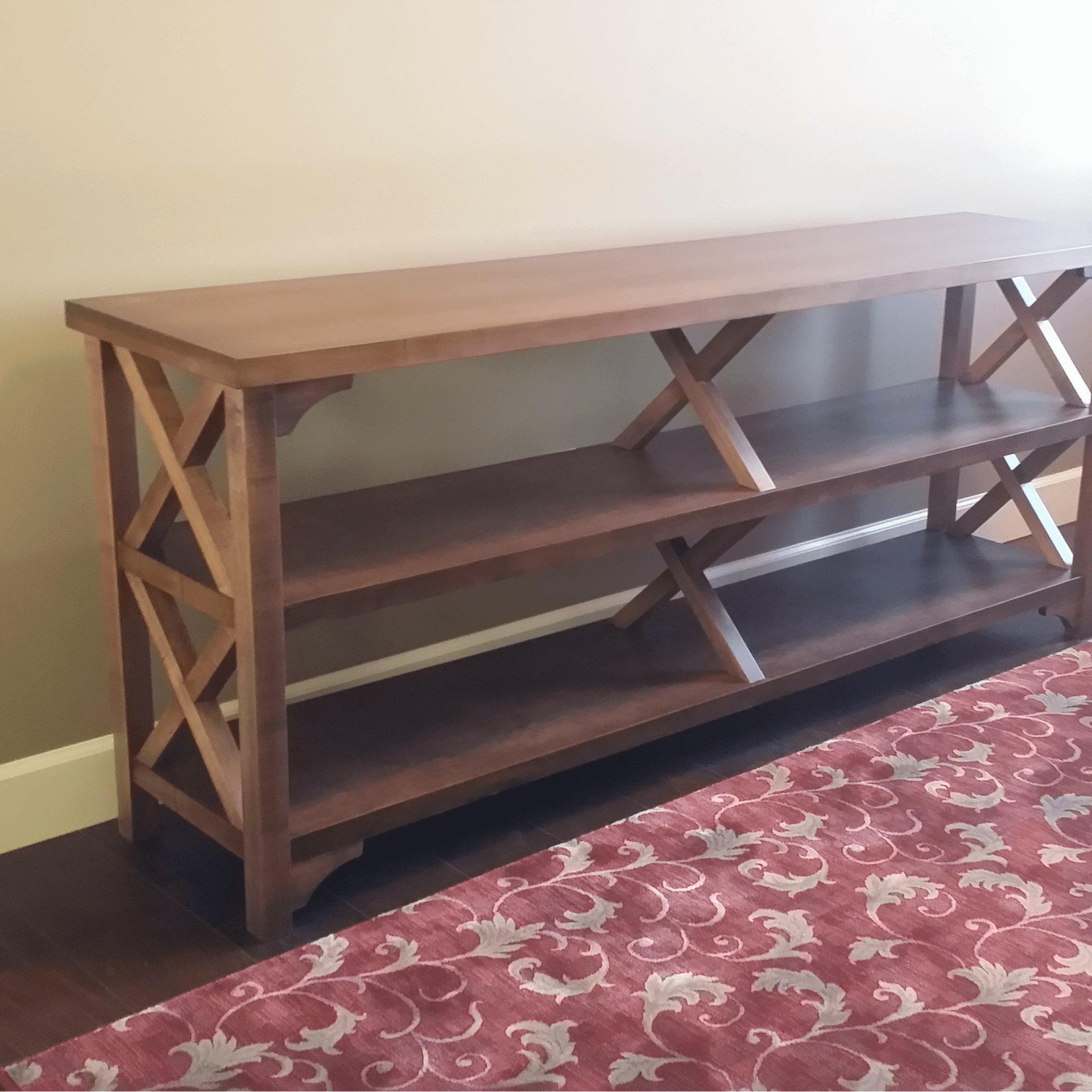 A wooden shelf is sitting next to a red rug