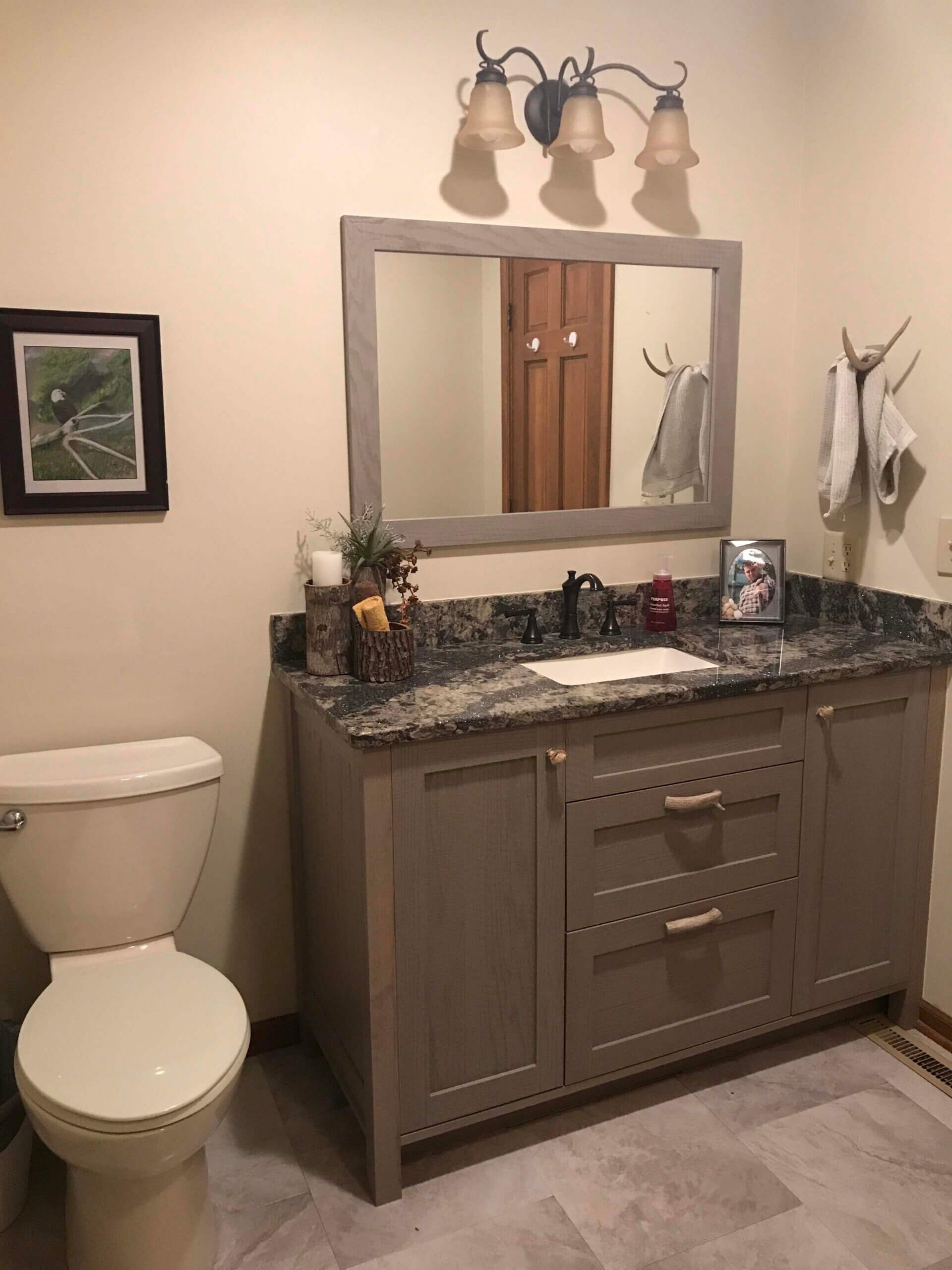 A bathroom with a toilet , sink , mirror and vanity.