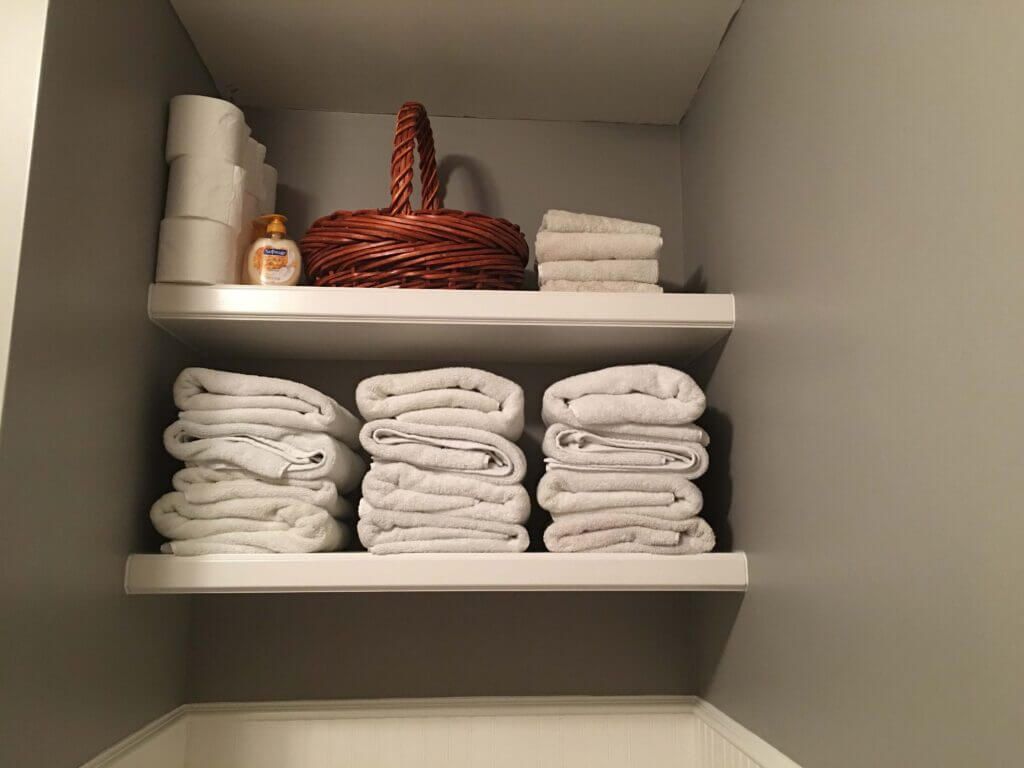 A bathroom shelf filled with towels and toilet paper