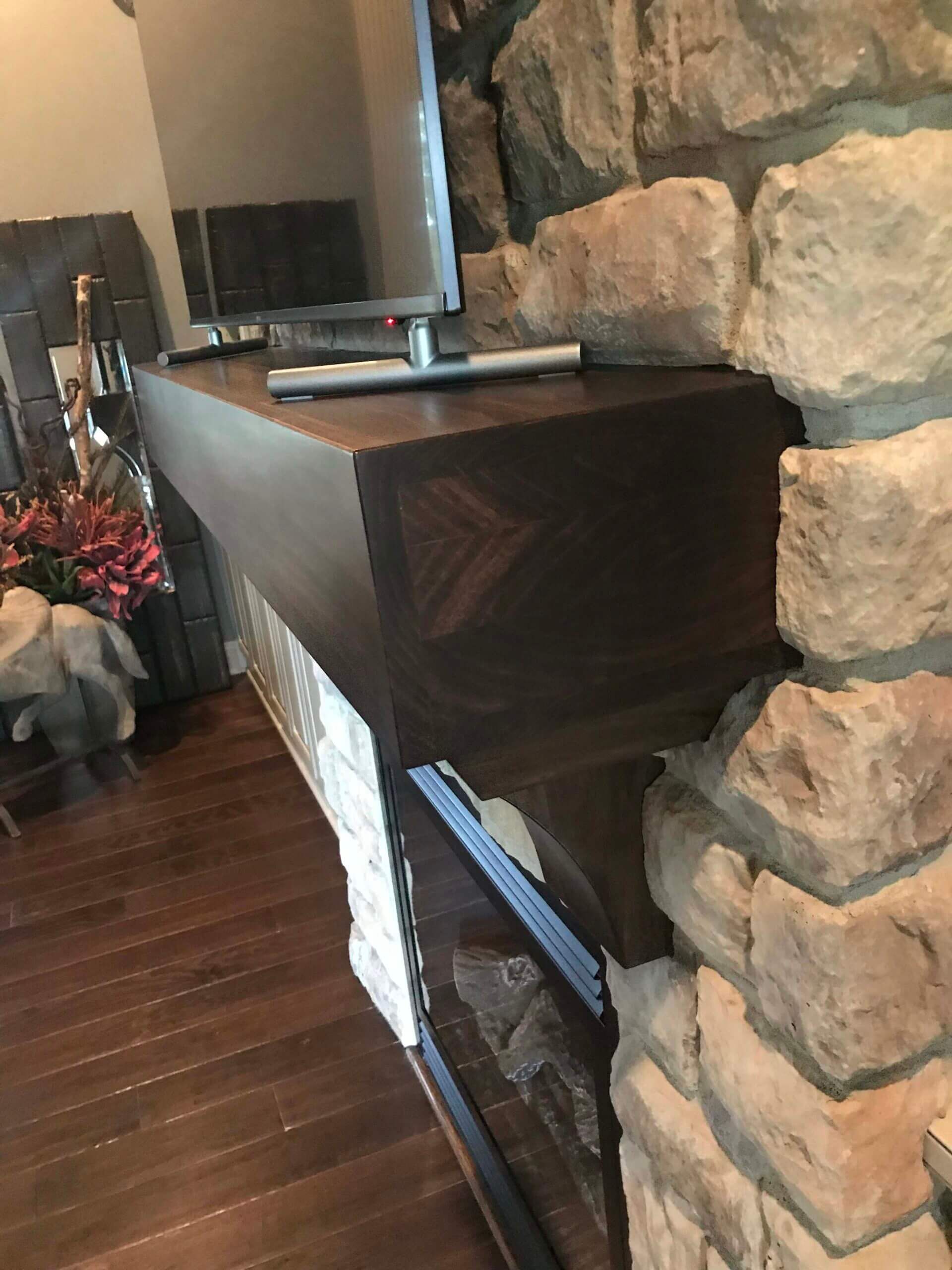 A television is sitting on top of a wooden mantle next to a stone fireplace.