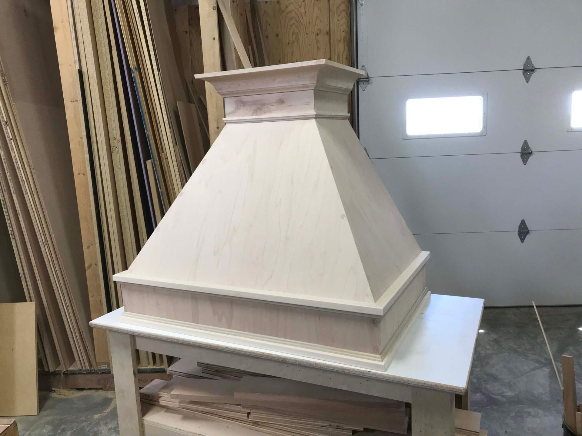 A wooden hood is sitting on top of a table in a garage.