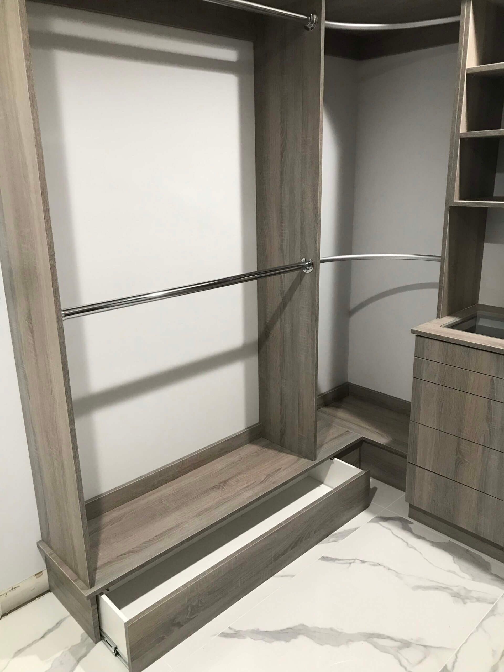 An empty closet with a drawer underneath it